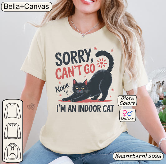 Person wearing a t-shirt with a cat graphic and text, sitting indoors.