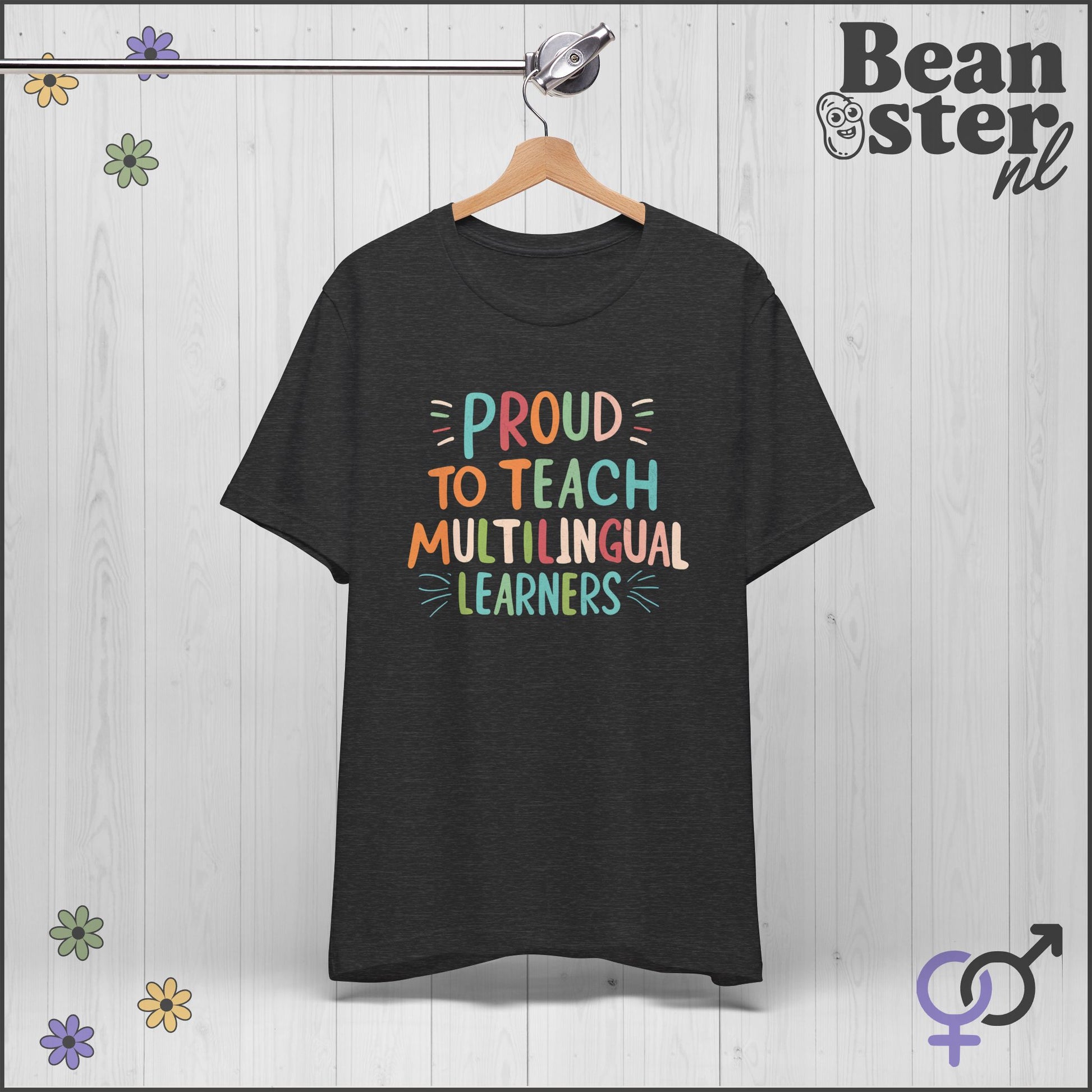 Black t-shirt with colorful text 'Proud to Teach Multilingual Learners' on a hanger against a light wooden background.