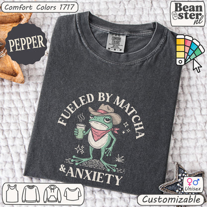 Dark gray t-shirt with a frog graphic and text 'Fueled by Matcha & Anxiety' on a textured surface.