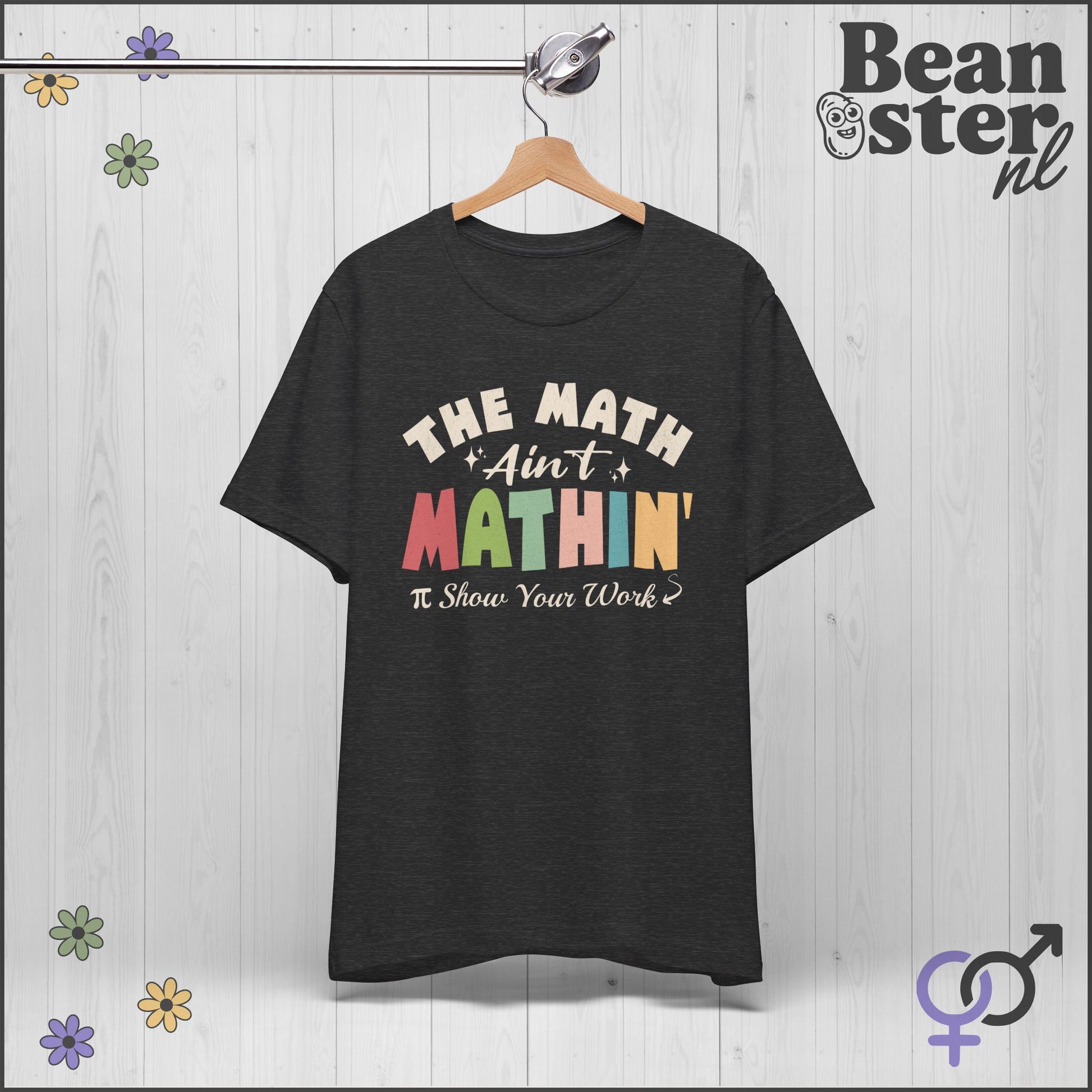 Black t-shirt with colorful text on a hanger against a light wooden background