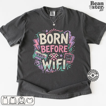 A dark gray graphic t-shirt featuring the text 'BORN BEFORE WIFI' in a retro neon style with cassette tapes and lightning bolts. 