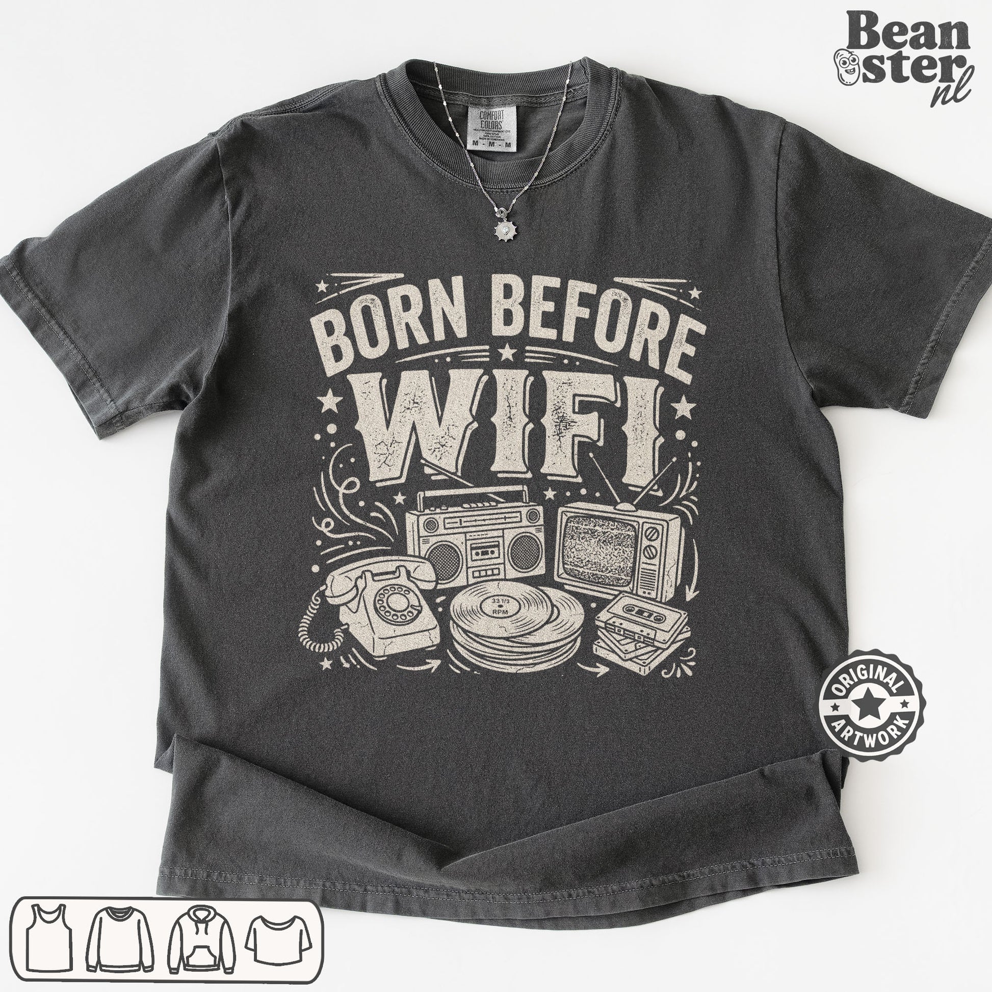 A dark gray graphic t-shirt laid flat on a white background, featuring a white distressed print that reads 'BORN BEFORE WIFI' above retro electronic illustrations.
