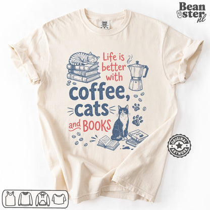 A cream-colored short-sleeve t-shirt with a graphic print that reads 'Life is better with coffee, cats and BOOKS' in red and navy blue text, accompanied by illustrations of a sleeping cat on books, a coffee maker, a sitting cat, and paw prints. The brand logo 'Beanster nl' is visible in the top right corner.