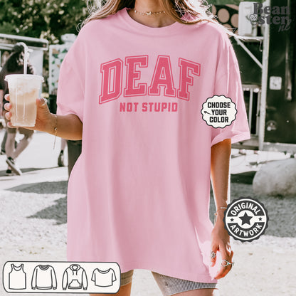 Person wearing a pink 'DEAF NOT STUPID' t-shirt outdoors.