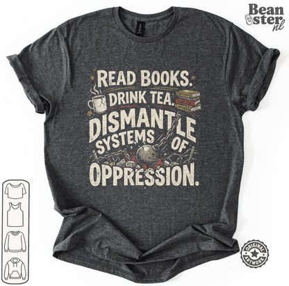 A dark heather gray graphic t-shirt featuring the text 'READ BOOKS DRINK TEA DISMANTLE SYSTEMS OF OPPRESSION' in distressed cream lettering, accompanied by illustrations of a mug, tea cup, books, and a globe. 