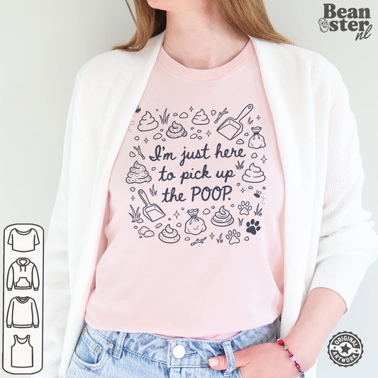 A woman wearing a light pink graphic t-shirt with a black line art design of poop icons and the text 'I'm just here to pick up the POOP'. She is wearing a white cardigan and blue jeans.