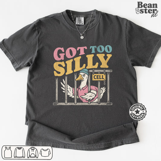 A dark gray graphic t-shirt featuring a cartoon duck in a pink pig costume behind bars with the text 'GOT TOO SILILY' in pink, blue, and yellow. The t-shirt is displayed flat against a white background with a 'Beanster nl' watermark in the top right corner.