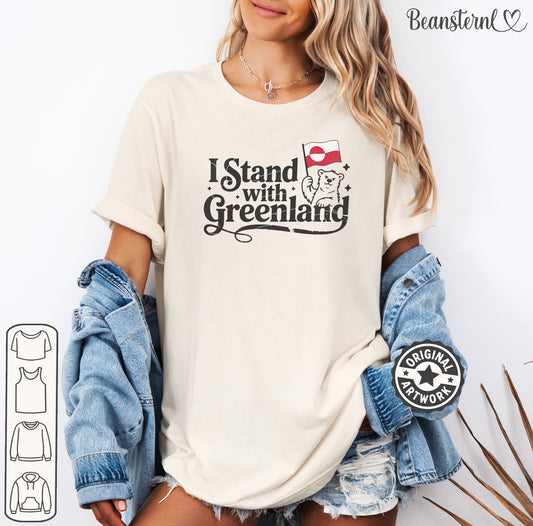 Person wearing a t-shirt with 'I Stand with Greenland' text and flag design, holding denim jacket.