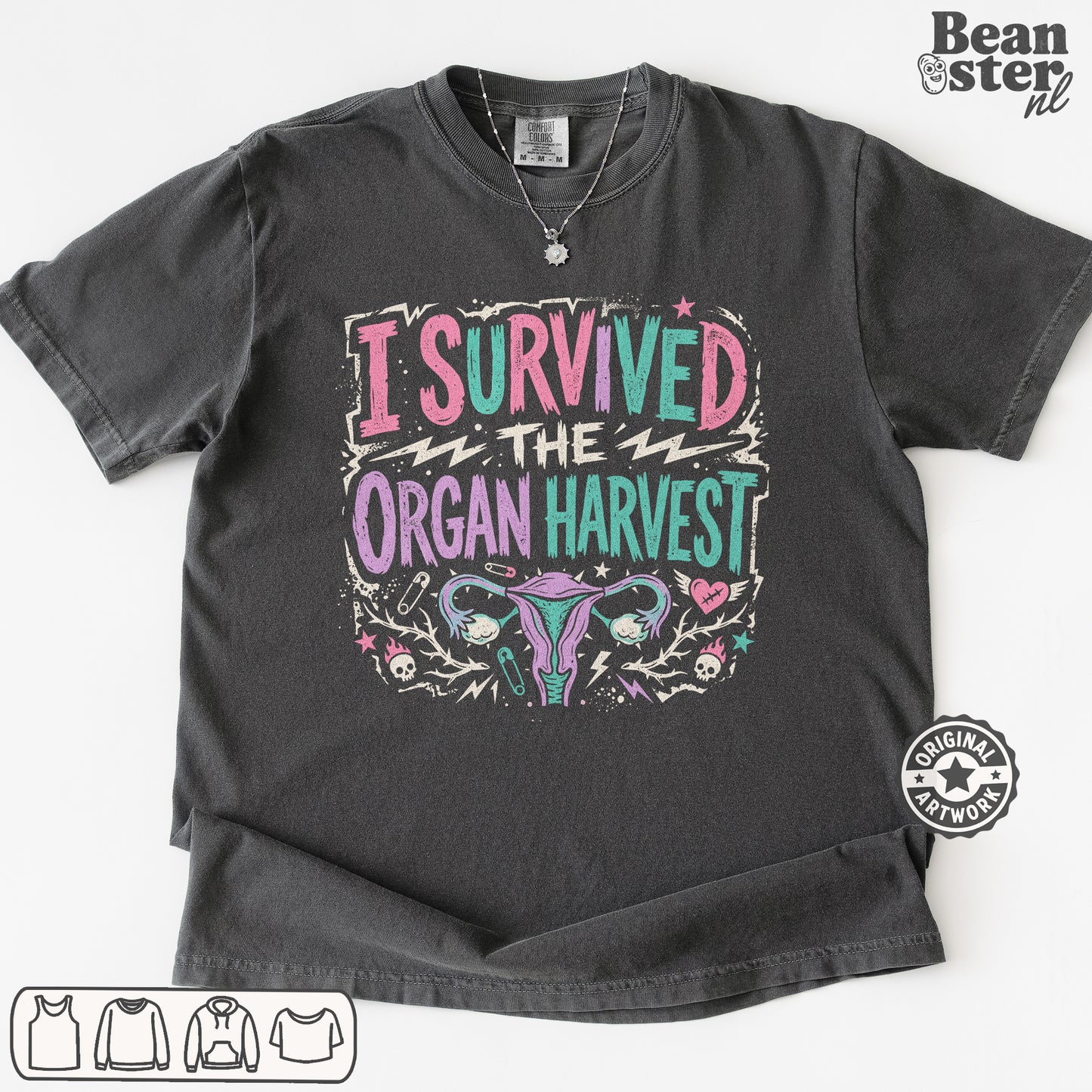 A dark gray graphic t-shirt featuring the text 'I SURVIVED THE ORGAN HARVEST' in pink, teal, and white, with a stylized uterus illustration below. 