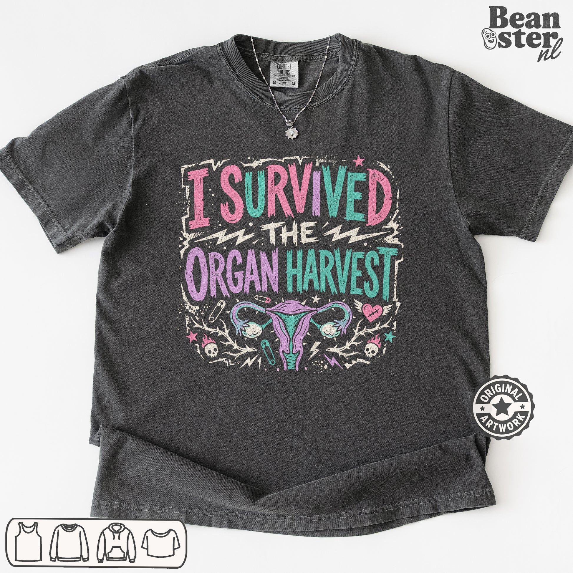 A dark gray graphic t-shirt featuring the text 'I SURVIVED THE ORGAN HARVEST' in pink, teal, and white, with a stylized uterus illustration below. 