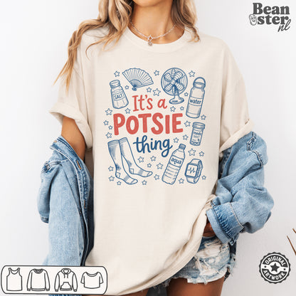 A woman wearing an oversized cream-colored graphic t-shirt with blue and red text reading 'It's a POTSIE thing' surrounded by doodles of bottles, socks, and a fan. She has a light blue denim jacket draped off her shoulders and distressed denim shorts, set against a plain white background.