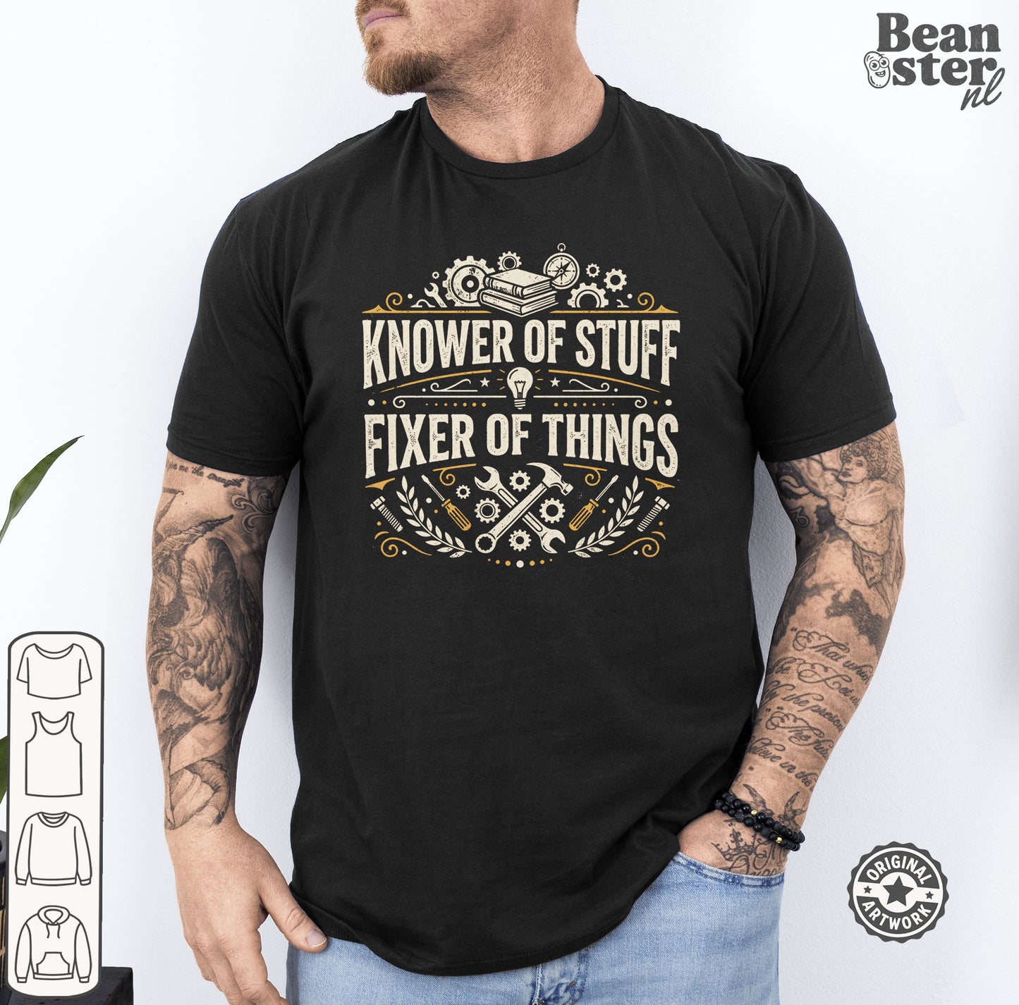 A man wearing a black graphic t-shirt with the text 'KNOWER OF STUFF FIXER OF THINGS' in a vintage cream and gold design. The photo is taken against a white wall, with a 'Beanster.