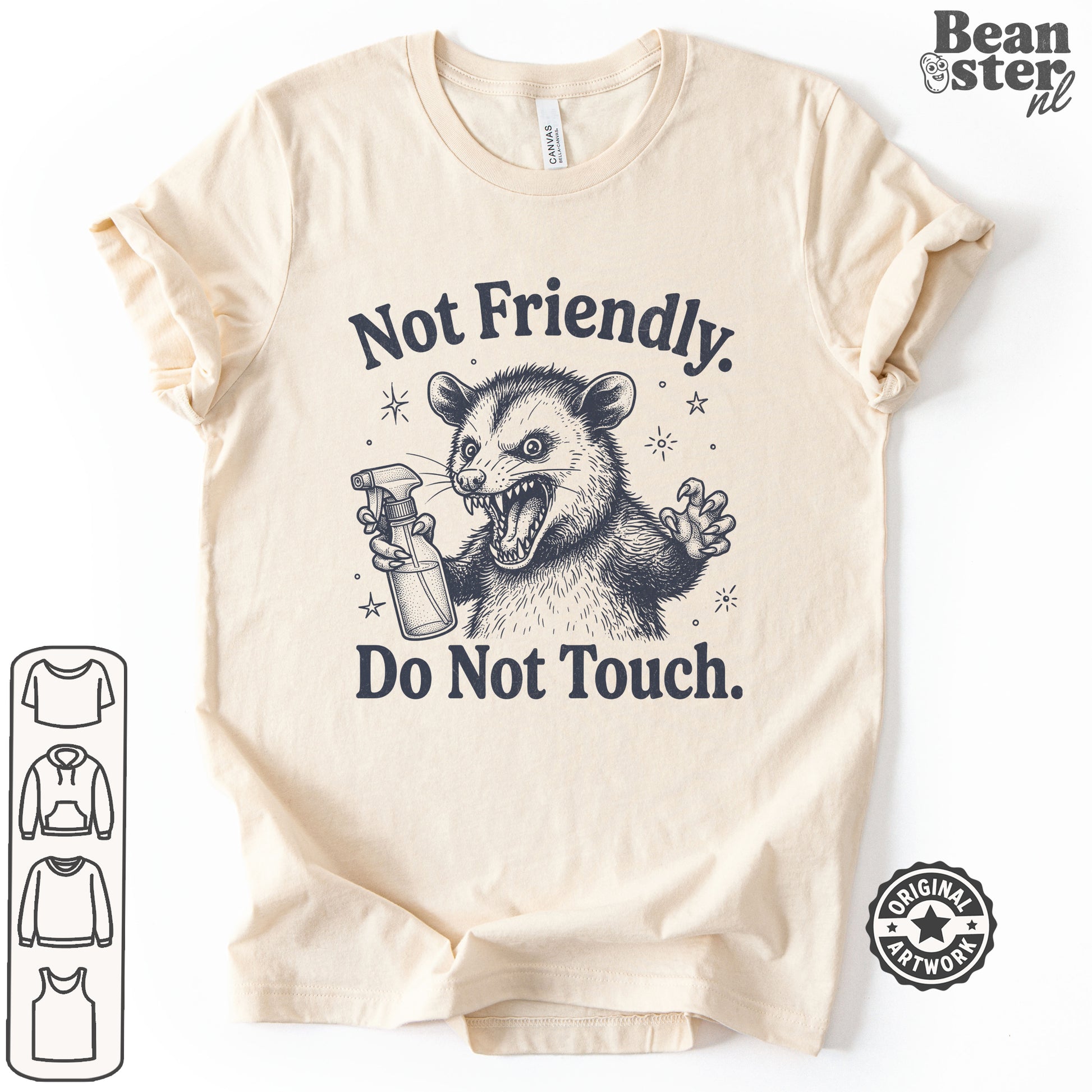 A beige short-sleeve t-shirt with a dark graphic of a mischievous possum holding a spray bottle, accompanied by the text 'Not Friendly. Do Not Touch.
