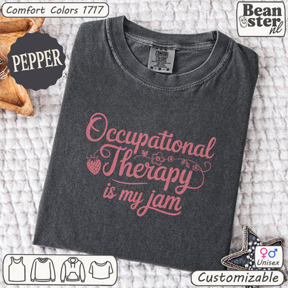 Folded dark gray t-shirt with pink text 'Occupational Therapy is my jam' on a textured surface, featuring Beanster branding.