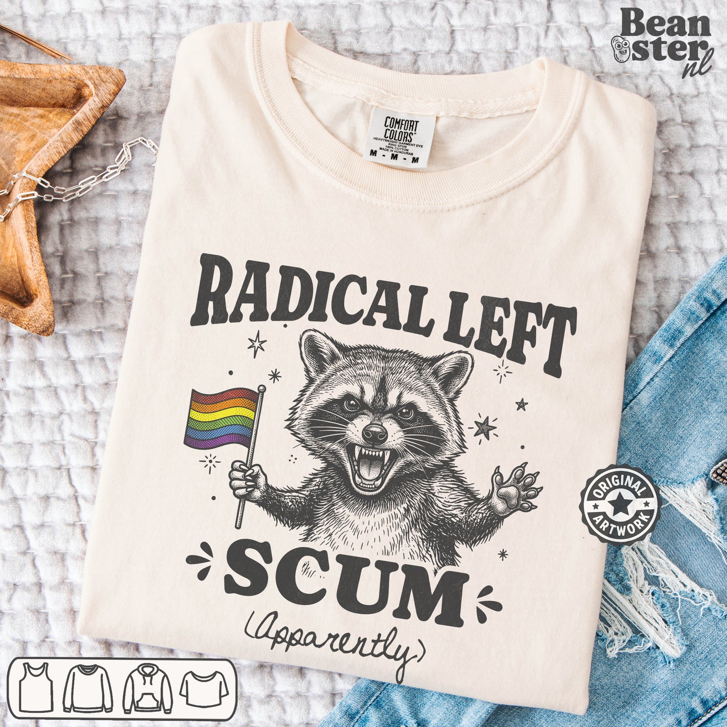 A folded cream-colored t-shirt with a black graphic of a raccoon holding a rainbow flag, surrounded by the text 'RADICAL LEFT SCUM (Apparently)'. 