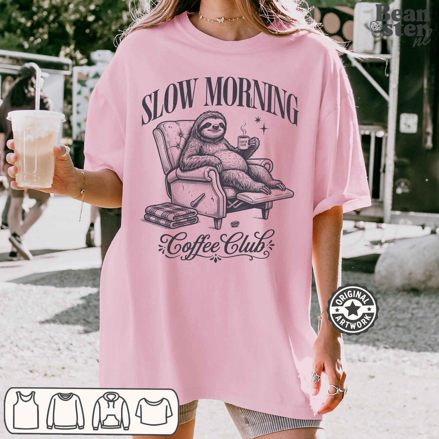 Person wearing a pink t-shirt with a sloth graphic and 'Slow Morning Coffee Club' text, holding a drink.