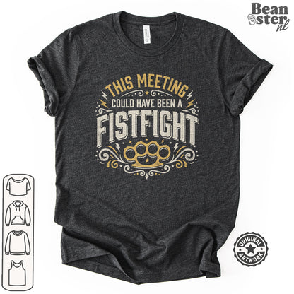 A dark heather gray graphic t-shirt featuring the text 'THIS MEETING COULD HAVE BEEN A FISTFIGHT' in distressed cream and gold lettering, with a gold brass knuckle graphic below. The t-shirt is displayed on a clean white background with a 'Beanster.